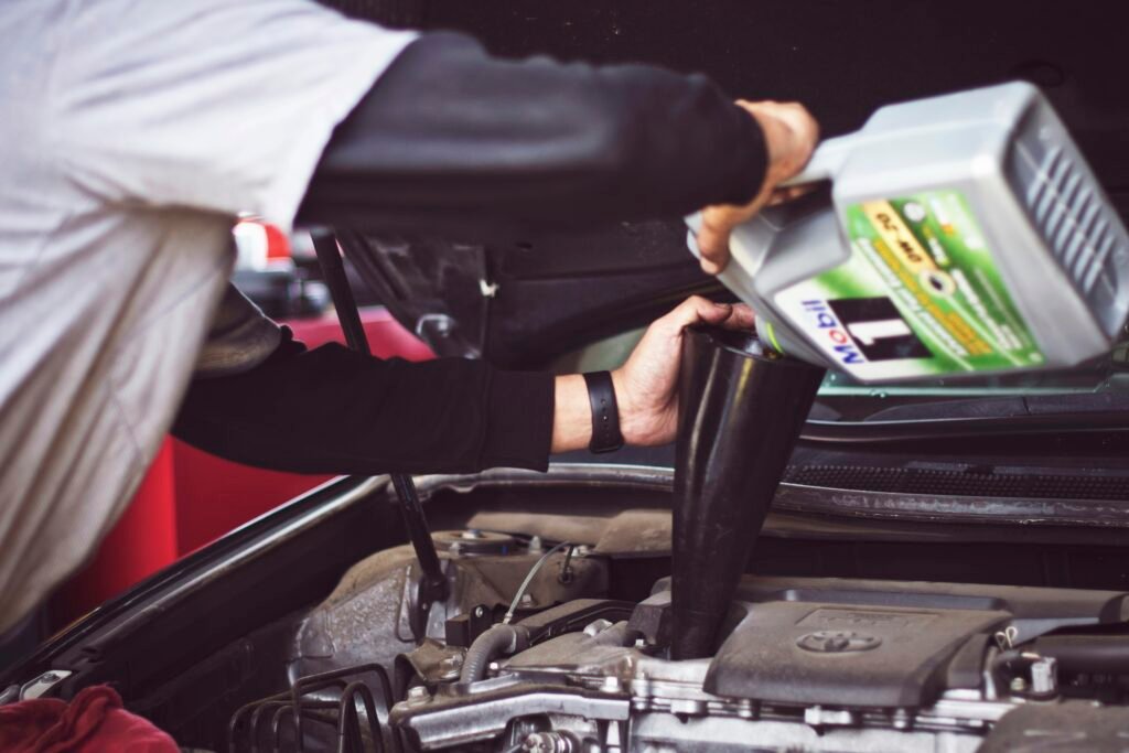 Technician pouring fresh motor oil into a car engine during an oil change in Plantation, FL